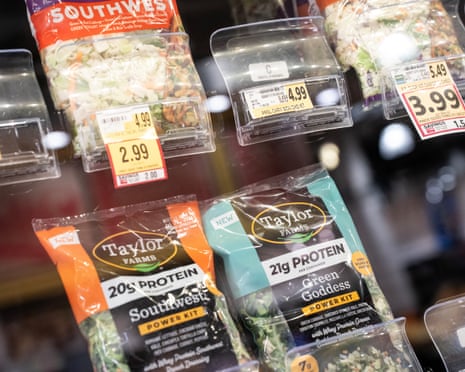 packaged salad products displayed for sale in a supermarket refrigerator