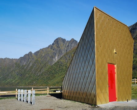 Senja’s ‘golden toilet’, a gold-shingled triangular building with a red door, stands before mountains.