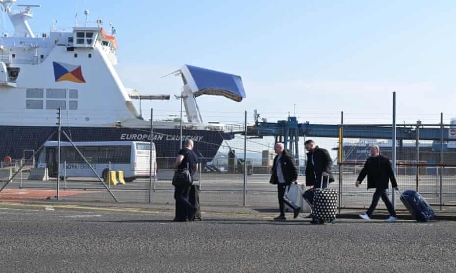 Ship workers are seen carrying their suitcases after disembarking from a P&O ferry