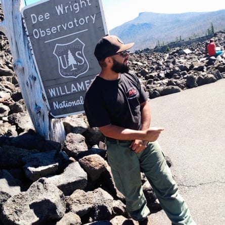 A man stands by a sign that reads ‘Dee Wright Observatory’
