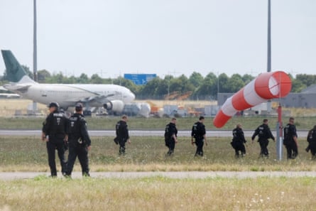 Police officers walk across a field at the airport