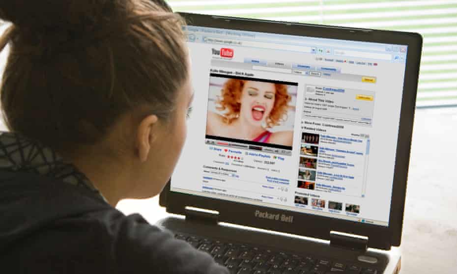 A teenage girl watching a Kylie Minogue Youtube video on a laptop. The length of time children spend watching screens is frequently a battleground in families.