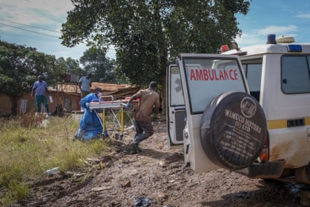 Men return a stretcher used for suspected Ebola victims to an ambulance after washing.