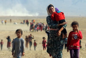Displaced people from the minority Yazidi community, fleeing violence from forces loyal to the Islamic State in Sinjar town, walk towards the Syrian border on the outskirts of Sinjar mountain near the Syrian border town of Elierbeh of Al-Hasakah Governorate in this 11 August, 2014