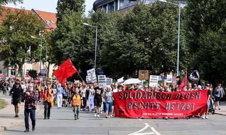 Protests walk along a street holding banners, including one across the leading walkers that says in German: ‘Solidarity against rightwing incitement!’