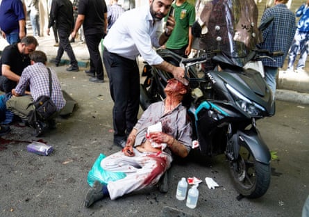 Injured peope are assisted in the street after an explosion in central Tehran.