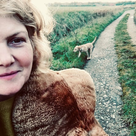 A blonde woman in her 50s walking her dog wearing a brown 1940s shearling wrap.