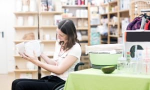 Young woman using wheelchair browsing in shop