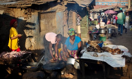 Women cook fish in the evening light to sell to passers by in one of the main streets of Kibera slum in Nairobi.