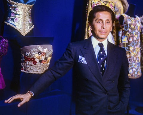 Valentino poses in front of some of his designs