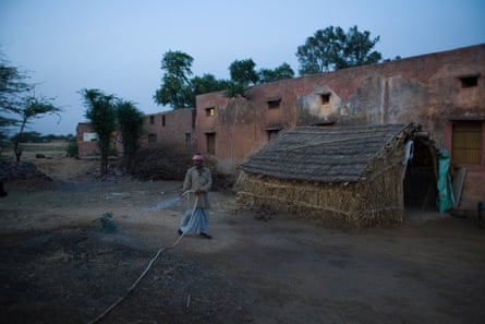 Azim is watering the ground to reduce the dust that gets stirred up in his house in Mewat District, haryana, India, on 31 March 2016.