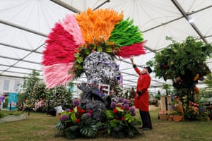 Chelsea pensioner Peter Wilson reaches up to touch the flowers of the multicoloured mohawk on the display of the punk’s head and shoulders, which stands twice his height