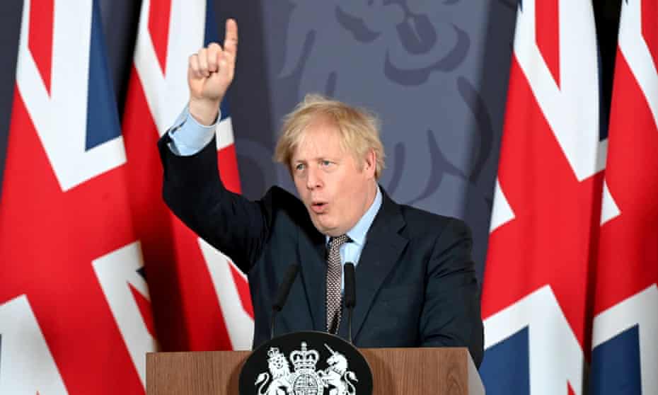 Boris Johnson, flanked by union flags, points to the ceiling at a news conference
