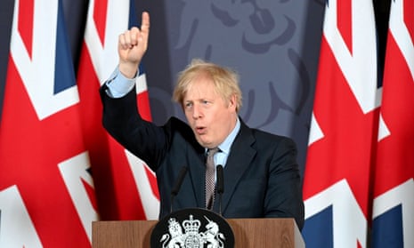 Boris Johnson, flanked by union flags, points to the ceiling at a news conference