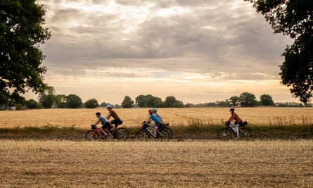 Riders cycle past fields in Norfolk on the Rebellion Way on a cloudy October day.