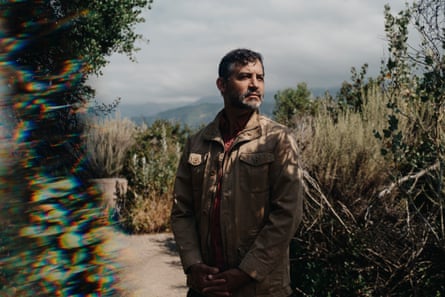 man posing outside amid brushy shrubs