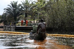 Members of the Nembe community paddle in a canoe after an oil spill