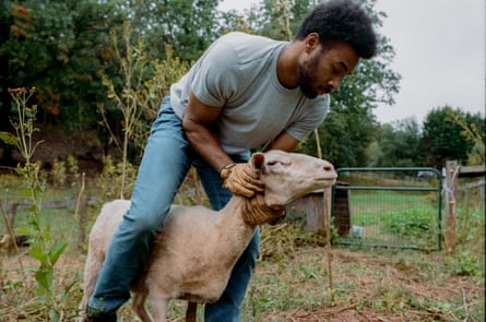 A young man holds a sheep.