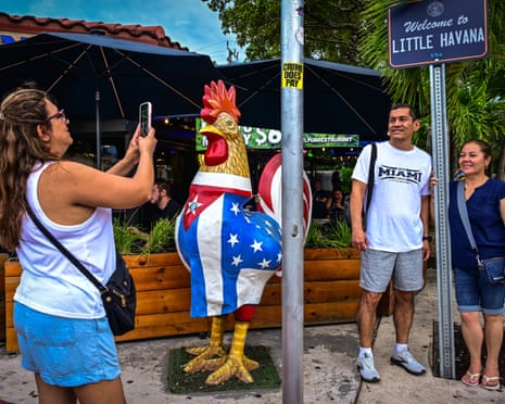 People pose for a photo next to a Little Havana sign and a giant rooster statue