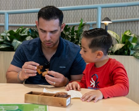 A man and boy sit at a table looking at a 3D wooden puzzle.