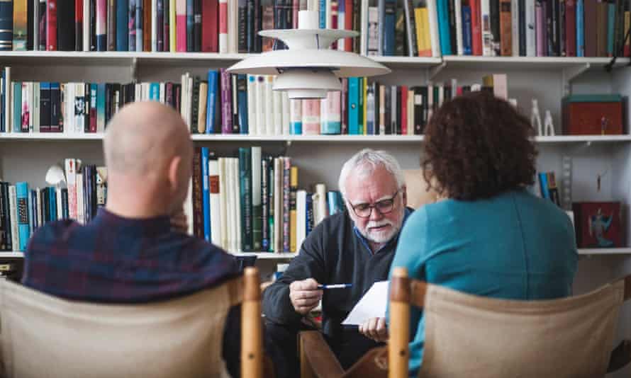 A counsellor in a book-lined room, facing a couple. 