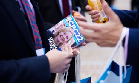 people talking with one holding pamphlet with picture of Liz Truss