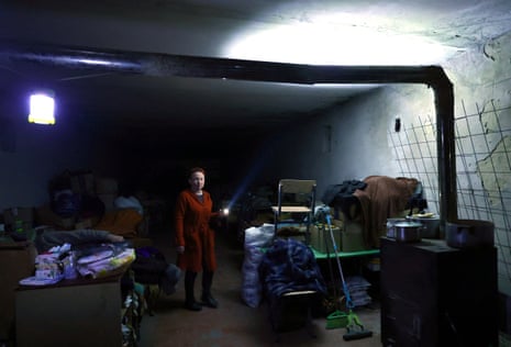 A uses a torch to make her way in a basement shelter in Velyka Novosilka near the frontline in Donetsk.