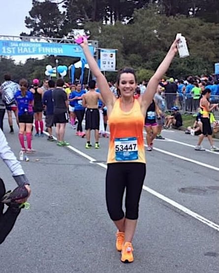a smiling young woman poses after running a half-marathon