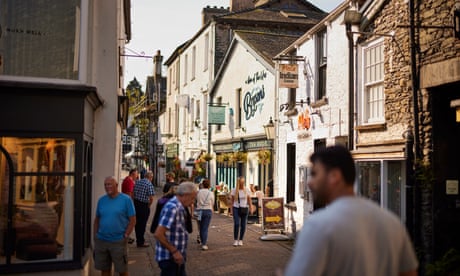 Ten or so people in short sleeves in a small picturesque street with shops