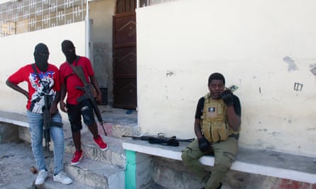 Gang leader Jimmy ‘Barbecue’ Chérizier speaks into his phone before a mission, as two of his men watch, in Port-au-Prince on Tuesday.