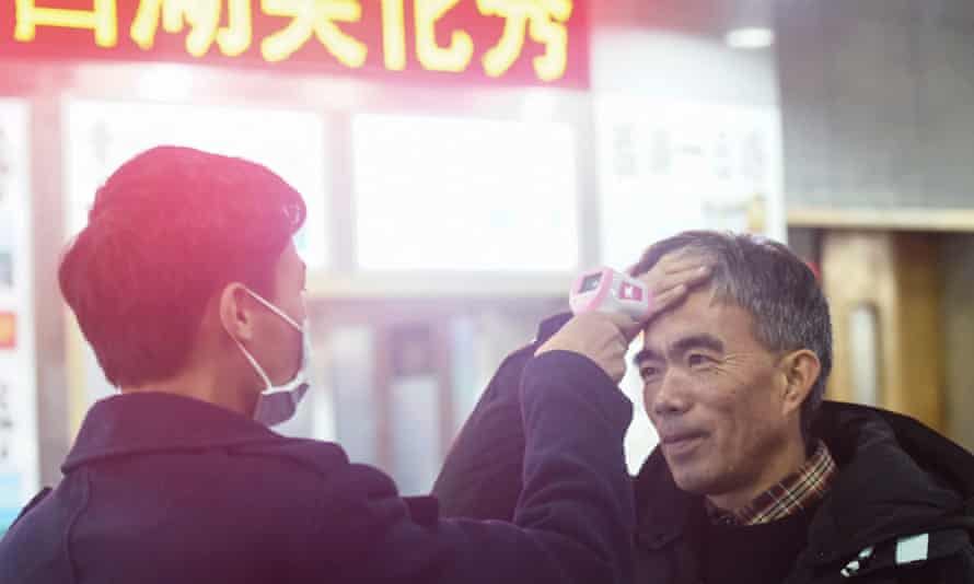 A staff member checks the body temperature of a passenger after a train from Wuhan arrived at Hangzhou Railway Station in Hangzhou.
