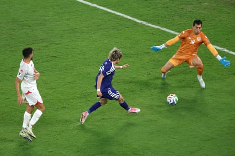 Junya Ito of Japan scores his team's third goal past Aymen Dahmen of Tunisia.