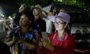   People are holding phones outside the cave rescue center in Thailand 