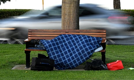 A person sleeps on a bench under a blanket