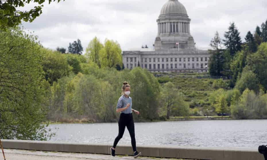 A person wears a mask while jogging near the capitol in Olympia, Washington. The head of the World Health Organization said more than 1bn vaccine doses have been given globally but 82% of them have been administered in high- and upper-middle-income countries.