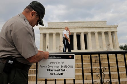 a man tying a ‘closed’ sign on a gate