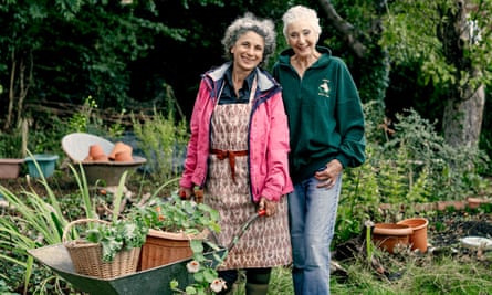 Rosa Mechoni, hands on a wheelbarrow, stands next to Helen Webster in Helen’s garden, both smiling
