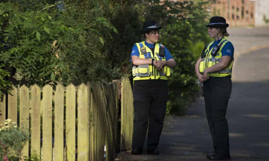 Two PCSOs stand outside a property during a search of a house in Pentwyn.