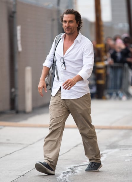 a man walking in a white button down shirt and khaki pants