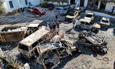 Aerial view of people standing before destroyed buildings at the site of al-Ahli Arab hospital in the aftermath of an overnight strike.