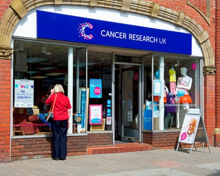 A Cancer Research UK charity shop, with a person looking through the window