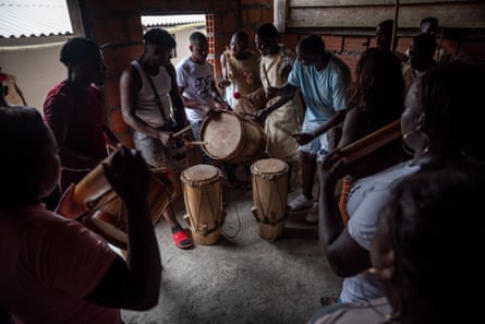 A group of men and woman standing together playing drum-like instruments