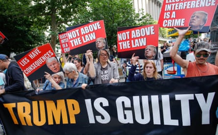 Protesters hold a 'Trump is guilty' banner.