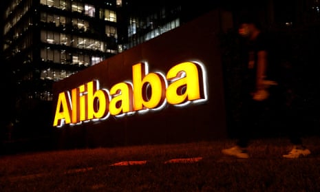 A man walks past a logo of Alibaba Group at its office building in Beijing.