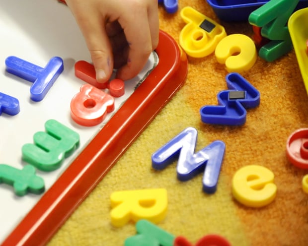 A child's hand placing letter magnets on a whiteboard