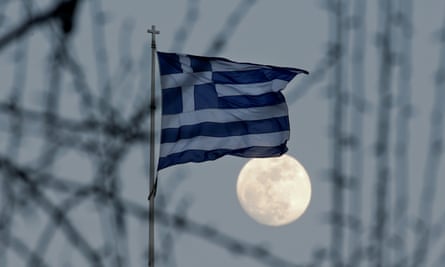 A Greek national flag flutters as the moon rises in Athens.