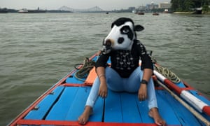 A woman in a cow mask sits on a boat