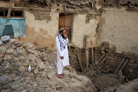 A man stands amid the rubble of a collapsed house