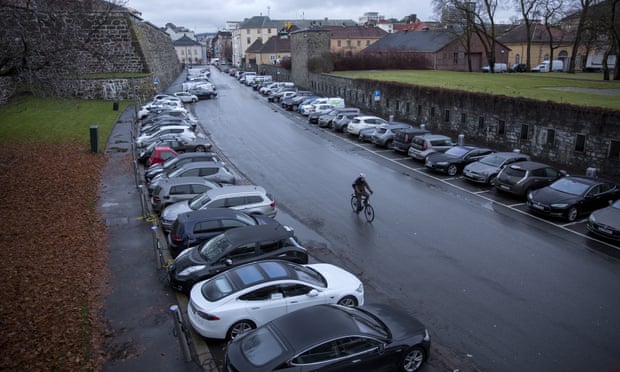 A cyclist rides past electric vehicles parked at charging stations at Kongens gate near Akershus festning in Oslo, Norway.