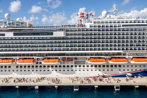 people walk near a cruise ship docked at a port